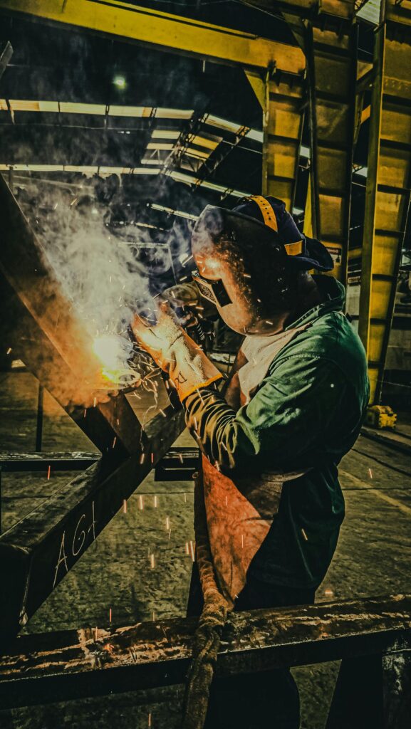 A skilled welder works on metal fabrication in a Brazilian factory, showcasing industrial precision.